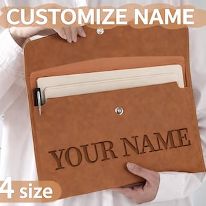 May include: A brown leather A4 size document holder with the text "YOUR NAME" engraved on the front. The holder has a snap closure and a pen holder. The words "CUSTOMIZE NAME" are at the top.