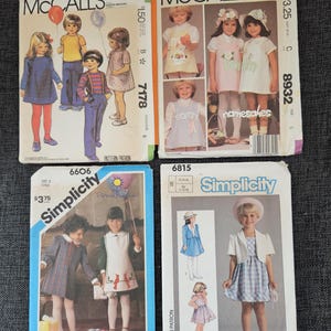May include: Four vintage sewing patterns for children's dresses. The patterns are for sizes 5 and 6. The patterns are from McCall's and Simplicity. The patterns feature illustrations of girls wearing the dresses.