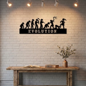 May include: A black metal wall art piece featuring a series of stick figures depicting human evolution, ending with a figure holding a whip over another figure on a leash. The word EVOLUTION is cut out in capital letters along the bottom base.
