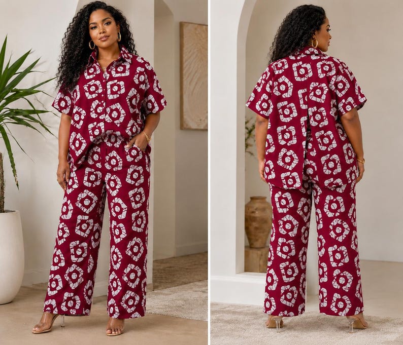May include: A two-piece set consisting of a short-sleeved button-down shirt and wide-leg trousers. The garment features a deep burgundy base color with a repeating white geometric pattern of interconnected shapes and lines throughout the fabric.