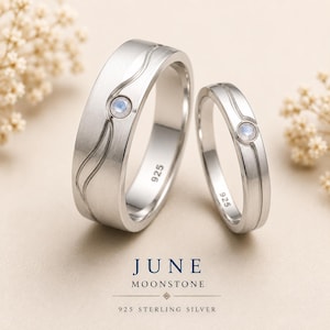 May include: Two 925 sterling silver rings featuring a brushed finish, a wavy engraved line, and a single round moonstone inlay. The interior of each band is stamped with 925. Text reads: JUNE MOONSTONE 925 STERLING SILVER.