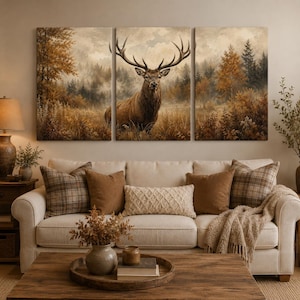 May include: A three-panel canvas wall art set depicting a majestic stag with large antlers standing in a misty autumn forest. The scene features warm brown, gold, and muted green tones, showcasing dense trees and tall grasses in a woodland landscape.