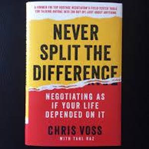 May include: A hardback book titled "NEVER SPLIT THE DIFFERENCE" by Chris Voss. The book has a yellow and red cover with black text. The subtitle reads "NEGOTIATING AS IF YOUR LIFE DEPENDED ON IT".