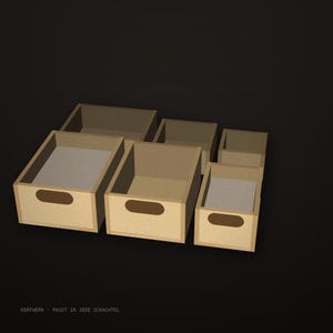 May include: A set of five light brown wooden storage boxes of varying sizes, each featuring a rectangular cutout handle on the front panel. The text KERFWERK - PASST IN JEDE SCHACHTEL is printed in small white letters at the bottom left corner.