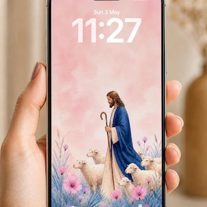 Könnte beinhalten: Ein Smartphone zeigt eine pastorale Szene mit einer Figur in blauem Gewand mit Stab, umgeben von Schafen und Blumen. Der Bildschirm zeigt Datum und Uhrzeit: Sonntag, 3. Mai, 11:27 Uhr.