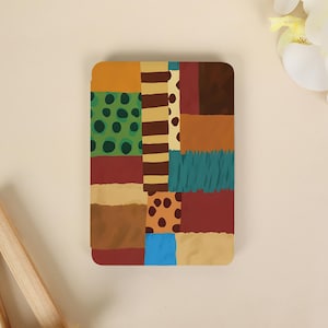 Peut inclure: Une coque de tablette rectangulaire présentant un motif patchwork de diverses couleurs et motifs, incluant du vert avec des points vert foncé, des rayures marron et beige, du jaune moutarde uni, du rouge profond, du bleu sarcelle et du beige à pois marron.