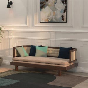 Pode incluir: Um divã de madeira com estrutura castanho-escura, estofamento bege claro e encosto capitonê. O divã é decorado com quatro almofadas quadradas em azul-marinho sólido e um padrão geométrico bicolor em verde-claro e bege.
