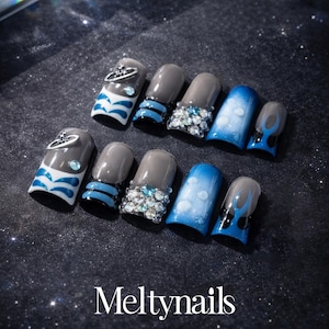 May include: A set of ten artificial nails in various designs. Some nails are gray with silver accents, others are blue with white wave patterns, and some are adorned with rhinestones. The text "Meltnails" is at the bottom.