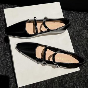 May include: A pair of black, glossy flats with pointed toes and double straps. The shoes have small silver buckles and are set on a white surface. The overall design is sleek and modern, suitable for various occasions.