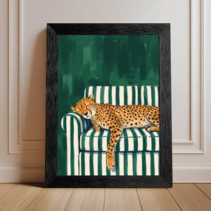 May include: Framed art print featuring a cheetah resting on a striped sofa. The cheetah has a tan coat with black spots. The sofa has green and white stripes, set against a dark green background. The frame is black.