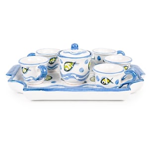 May include: A ceramic tea set featuring a rectangular tray, a lidded sugar bowl, and four small cups. The white pieces are decorated with hand-painted blue wavy lines, light blue polka dots, and small yellow and black fish motifs throughout.