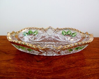 May include: A clear glass serving dish with a scalloped edge and gold trim. The dish has a green and gold floral design.
