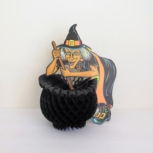May include: A black witch cutout with a black hat and a black cauldron. The witch is holding a broom and has a green and orange dress. The cauldron is made of black honeycomb paper.
