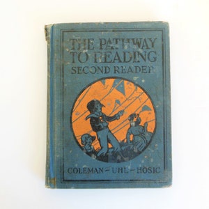 May include: A blue book with the title "The Pathway to Reading Second Reader" and the author's names "Coleman-Uhl-Hosic". The cover features an illustration of children flying kites.