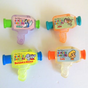 May include: Four plastic toy water guns featuring characters from the Disney movie The Rescuers Down Under. The guns are clear and show the characters Wilbur, Jake, Bernard & Bianca, and Cody. Each gun has a different color.