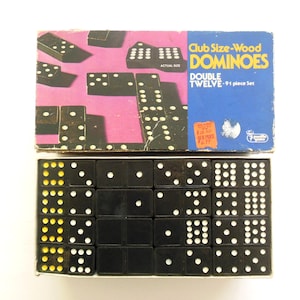 May include: A vintage Club Size-Wood Dominoes set. The box is blue and pink with the words "DOUBLE TWELVE - 91 piece Set". The dominoes are black with white and yellow dots. The set is in its original box.