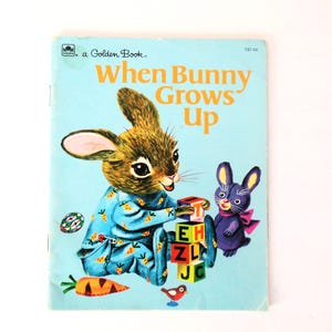 May include: A vintage Golden Book titled "When Bunny Grows Up" featuring a brown bunny in blue pajamas playing with blocks and a purple bunny. The book cover is blue with a yellow border.
