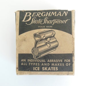 May include: A brown cardboard box with black text and a black and white illustration of a skate sharpener. The text on the box reads "Berghman Skate Sharpener Trade Mark" and "An individual abrasive for all types and makes of ice skates."
