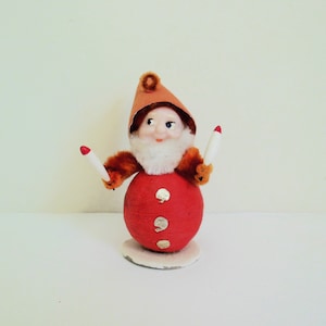 May include: A vintage Christmas gnome figurine with a red and orange outfit, white beard, and white and red drumsticks.