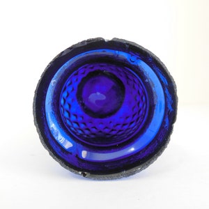 May include: A cobalt blue glass bowl with a textured, diamond-shaped pattern on the inside. The bowl has a slightly rough, textured rim.
