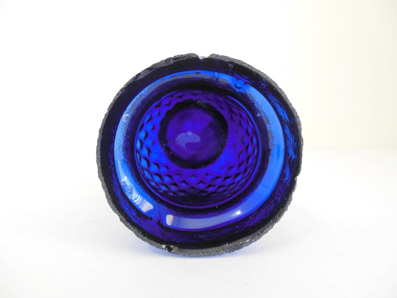 May include: A cobalt blue glass bowl with a textured, diamond-shaped pattern on the inside. The bowl has a slightly rough, textured rim.