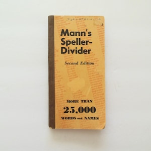 May include: A vintage copy of "Mann's Speller-Divider, Second Edition" with a worn, tan cover and brown spine. The cover features black text, including "More Than 25,000 Words and Names". The book is on a white background.