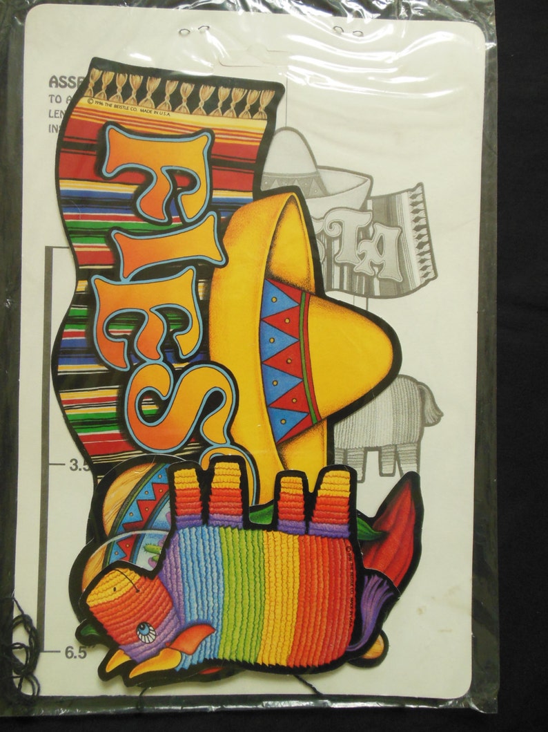 May include: A set of colorful paper cutouts for a fiesta party. The set includes a sombrero, a donkey, a banner that says "Fiesta", and a banner that says "Ta!" The cutouts are on a white background.
