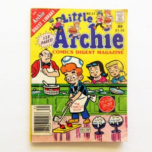 May include: A vintage "Little Archie" comic book with a yellow cover. The cover features cartoon illustrations of Archie and friends, along with the text "Comics Digest Magazine". The comic book has 128 pages and is marked with a price of $1.35.