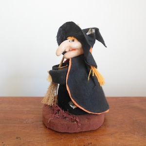 May include: A vintage Halloween witch doll with a black hat, orange and black dress, and a broom. The doll is made of fabric and has a painted face.