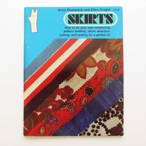 May include: A vintage book titled "SKIRTS" with a blue cover and colorful fabric swatches. The cover features text: "How to do your own measuring, pattern drafting, fabric selection, cutting, and sewing for a perfect fit."