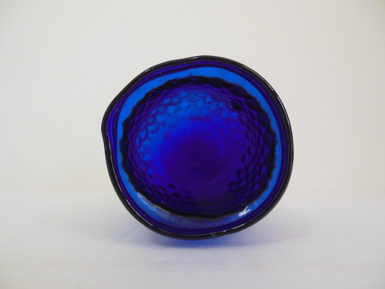 May include: The bottom of a cobalt blue glass pitcher with a textured surface.
