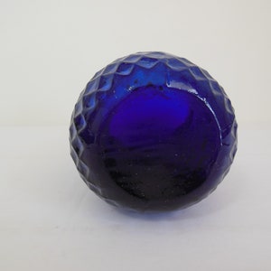 May include: A cobalt blue glass bottle with a textured, diamond-shaped pattern.