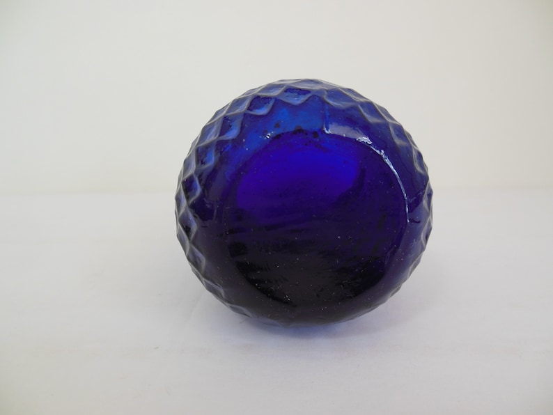 May include: A cobalt blue glass bottle with a textured, diamond-shaped pattern.
