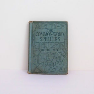 May include: A vintage blue book titled "The Common-Word Spellers Book Two" by Lewis. The cover features a decorative design of the alphabet.