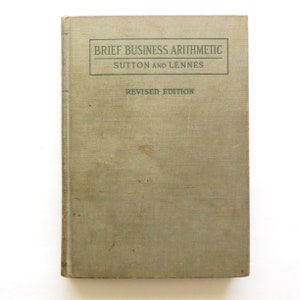 May include: A vintage book titled "Brief Business Arithmetic" by Sutton and Lennes. The book is a revised edition and has a green cloth cover.