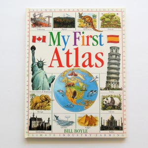 May include: A colorful book cover for "My First Atlas" by Bill Boyle. The cover features a world map, images of animals, buildings, and flags from different countries. The book is designed for children learning about geography.
