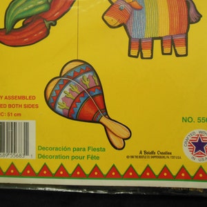 May include: A set of five colorful paper decorations for a fiesta. The decorations include a red chili pepper, a maraca, a donkey pi&ntilde;ata, and two green peppers. The decorations are printed on both sides and are easily assembled. The package includes the text "Decoraci&oacute;n para Fiesta" and "D&eacute;coration pour F&ecirc;te".