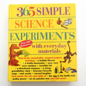 May include: A yellow book titled "365 Simple Science Experiments" with colorful text and illustrations. The book promises over 700 illustrations and experiments using everyday materials, including a bubble blower and a bottle barometer.