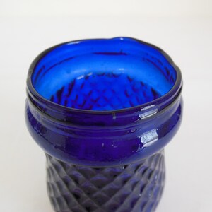 May include: Close-up of the top of a cobalt blue glass vase with a diamond pattern.