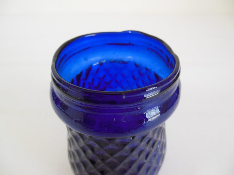 May include: Close-up of the top of a cobalt blue glass vase with a diamond pattern.