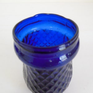 May include: A cobalt blue glass vase with a diamond pattern. The vase has a wide mouth and a rounded base.