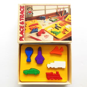 May include: A vintage children's toy set, "Place & Trace", featuring a yellow tray with colorful plastic shapes of a car, train, truck, airplane, rocket, and balloon. The box shows animal shapes and pencils. The box is beige with red and yellow text.