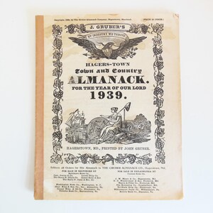 May include: Vintage 1939 Hagerstown Town and Country Almanack. The cover features an eagle emblem, decorative grape vines, and illustrations of a ship and a woman. The almanac is printed by John Gruber.