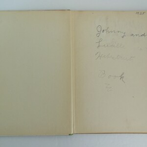 May include: A close-up of the inside cover of a book with handwritten text that reads "Johnny and Lucille Heffner's Book". The year 1928 is written in the top right corner.