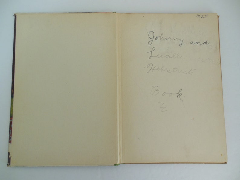 May include: A close-up of the inside cover of a book with handwritten text that reads "Johnny and Lucille Heffner's Book". The year 1928 is written in the top right corner.