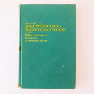 May include: A teal blue book with the title "PHYSICAL EDUCATION in the Elementary School Curriculum" in yellow text. The book is the third edition.