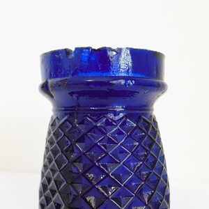 May include: A cobalt blue glass vase with a diamond pattern. The vase has a wide mouth and a narrow base.