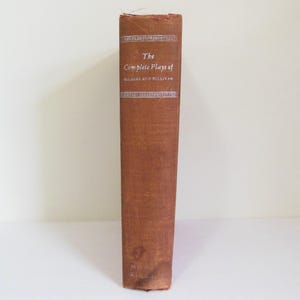 May include: A brown book with the title "The Complete Plays of Gilbert and Sullivan" printed in white on the spine.