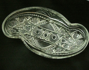 Könnte beinhalten: Eine klare Glasschale mit einem gewellten Rand und einem komplizierten geschliffenen Glasdesign. Die Schale hat ein Diamantenmuster mit einem Sternburst-Design in der Mitte.