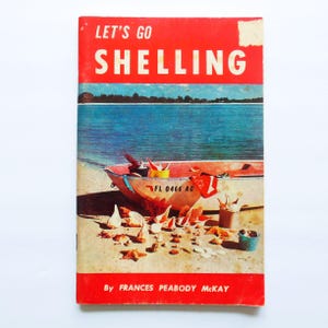 May include: A vintage book cover titled "Let's Go Shelling" with a red border. The cover features a beach scene with a boat, shells, and the text "By Frances Peabody McKay."